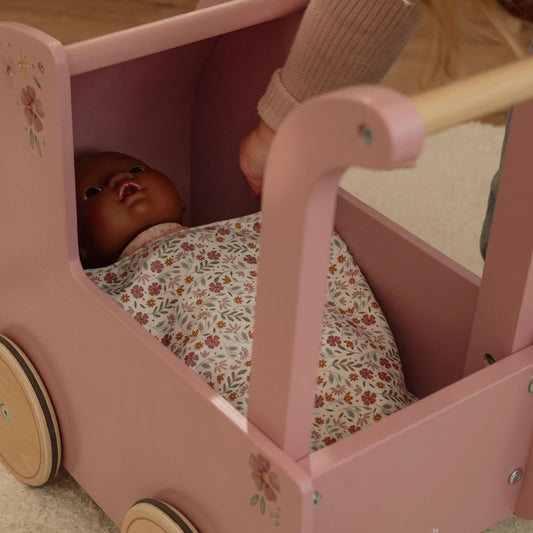 Baby doll in a pink wooden doll pram with floral bedding