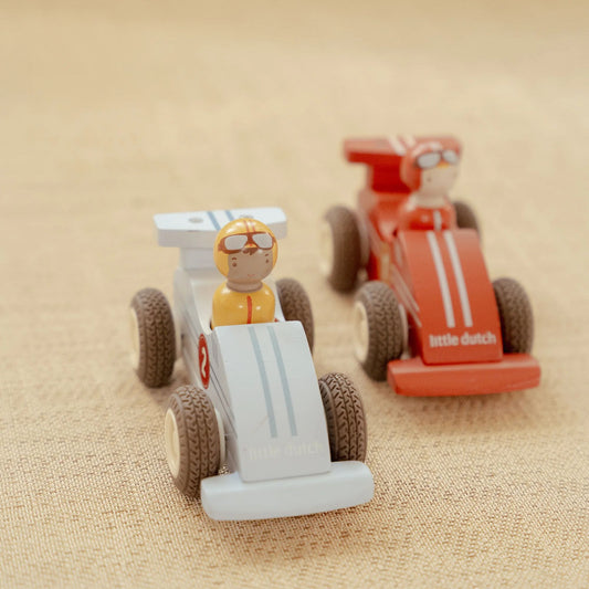 Two toy race cars with a driver figure on a beige fabric background