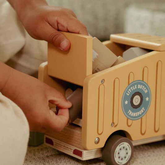 Child playing with a wooden toy truck labeled 'Little Dutch Transport'.