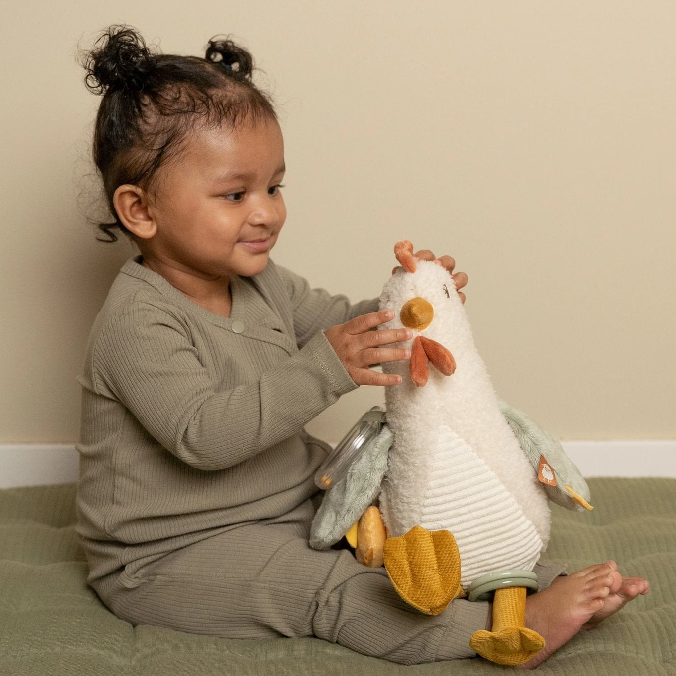 Child holding a plush toy on a bed with a plain background