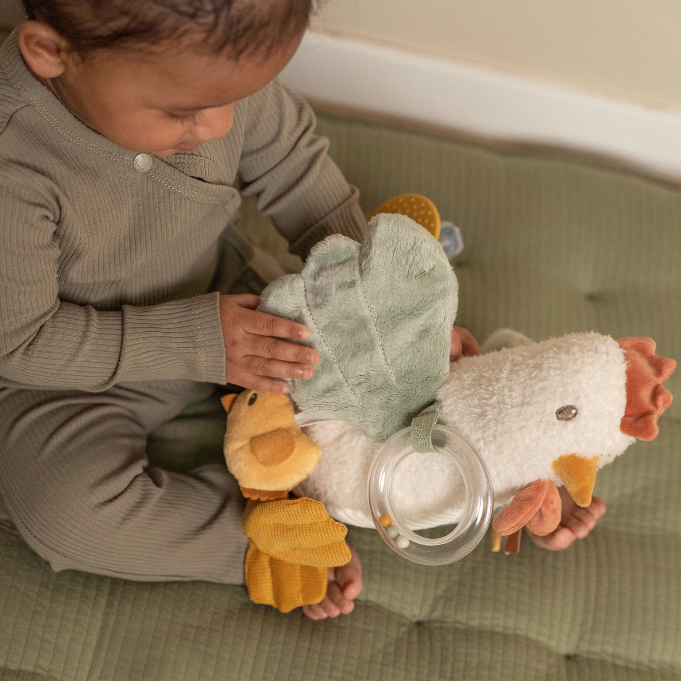 Child playing with a plush toy on a soft surface