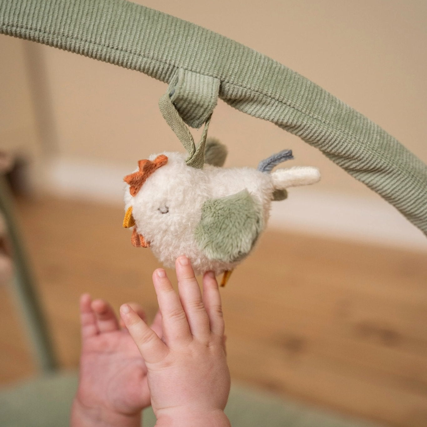 Baby reaching out to a plush toy hanging from a crib bar