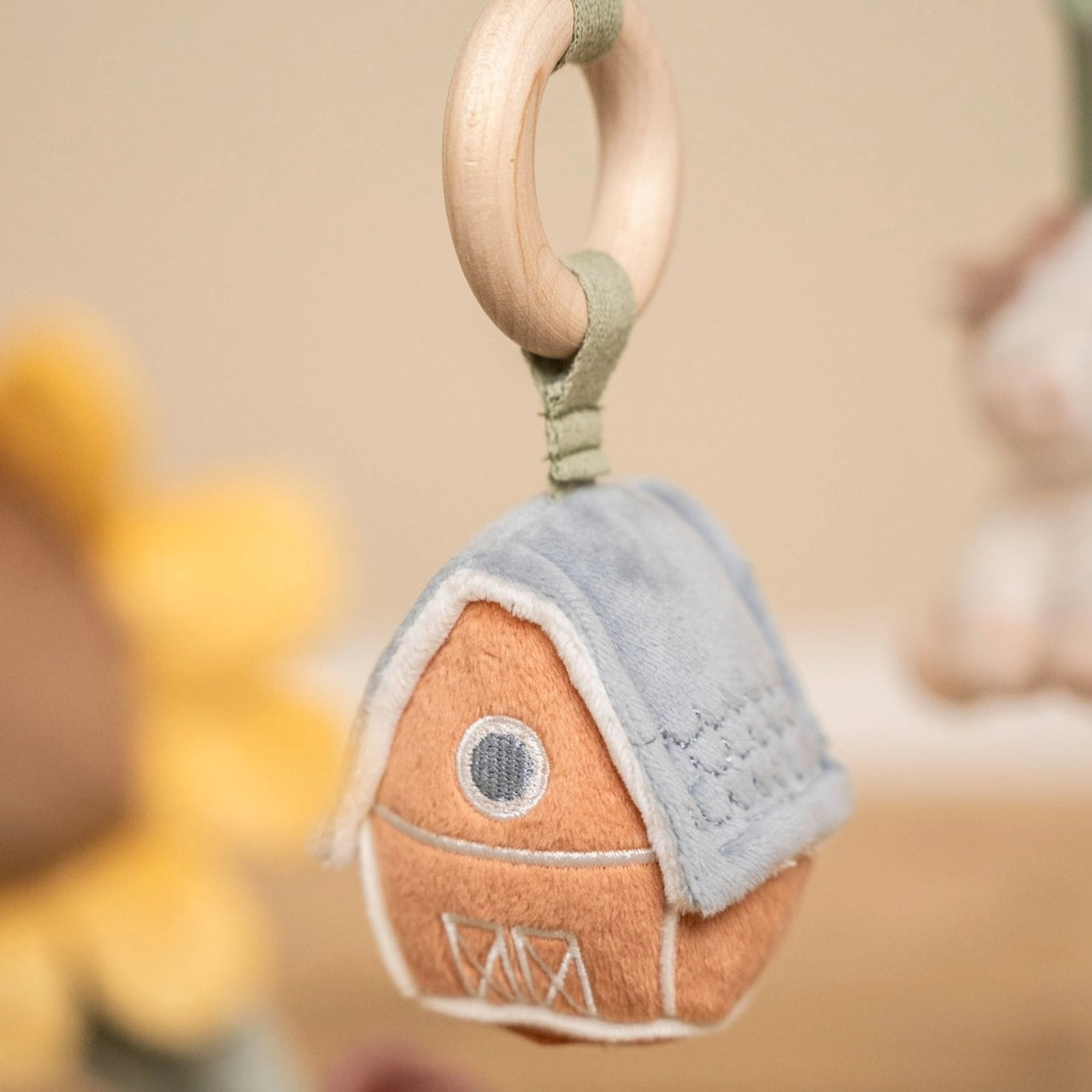 Felt house-shaped keychain with a wooden ring on a blurred background