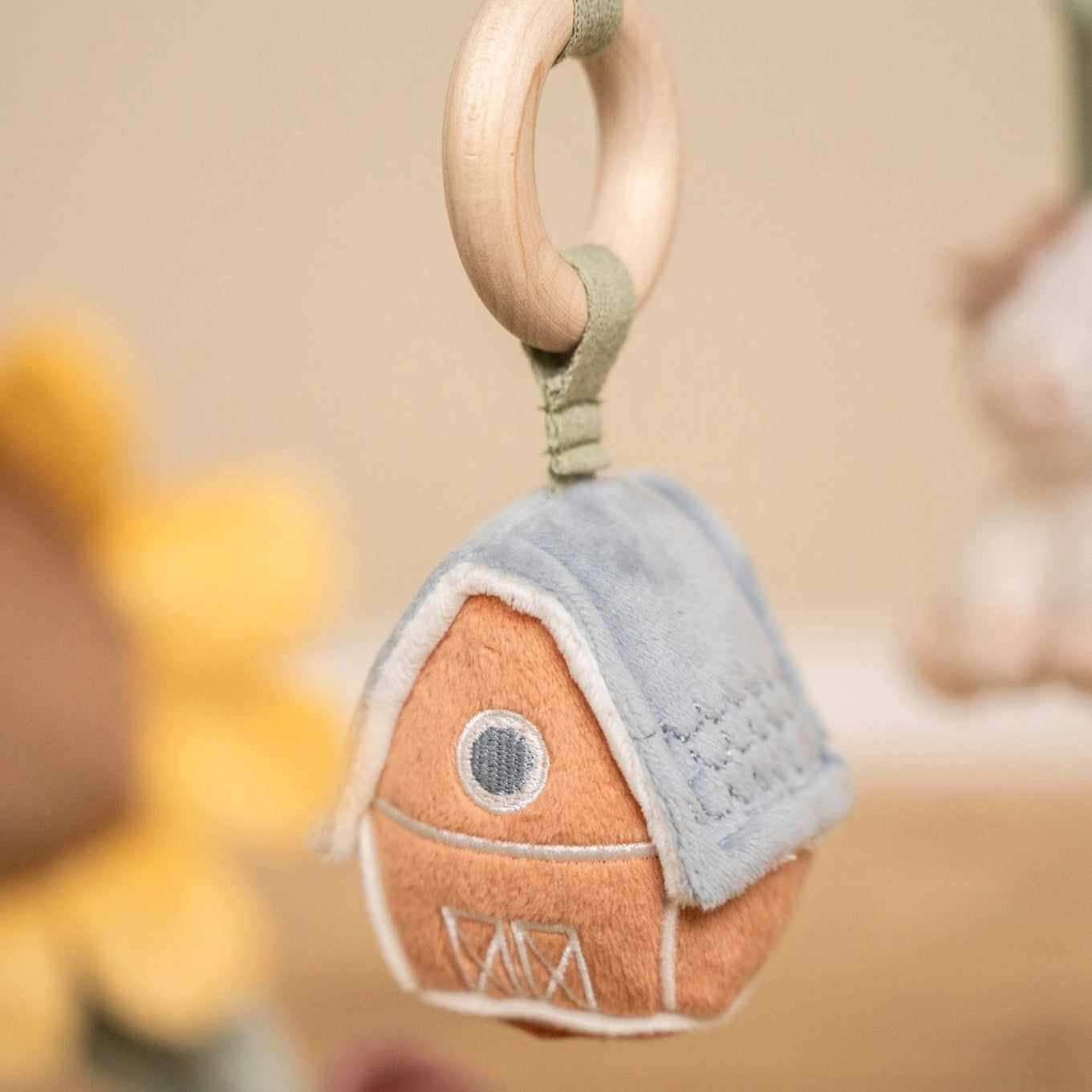 Felt house-shaped keychain with a wooden ring on a blurred background