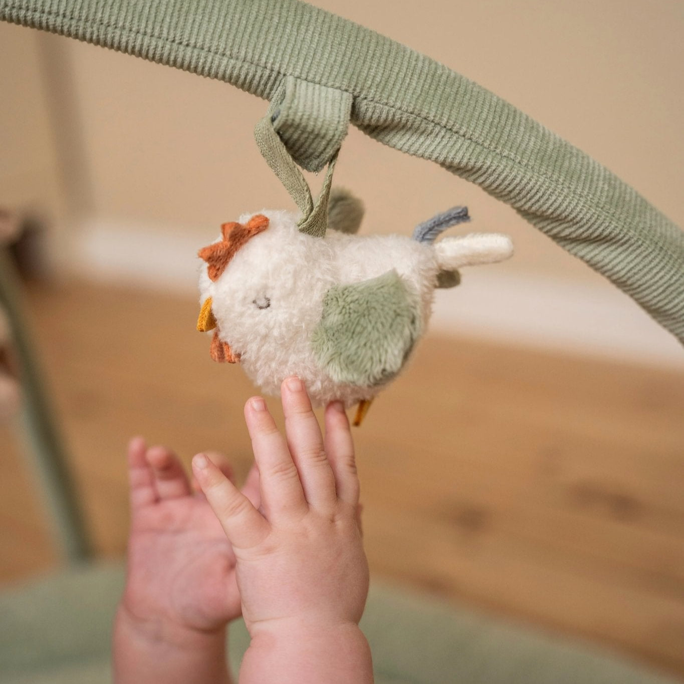 Baby reaching out to a plush toy hanging from a crib bar