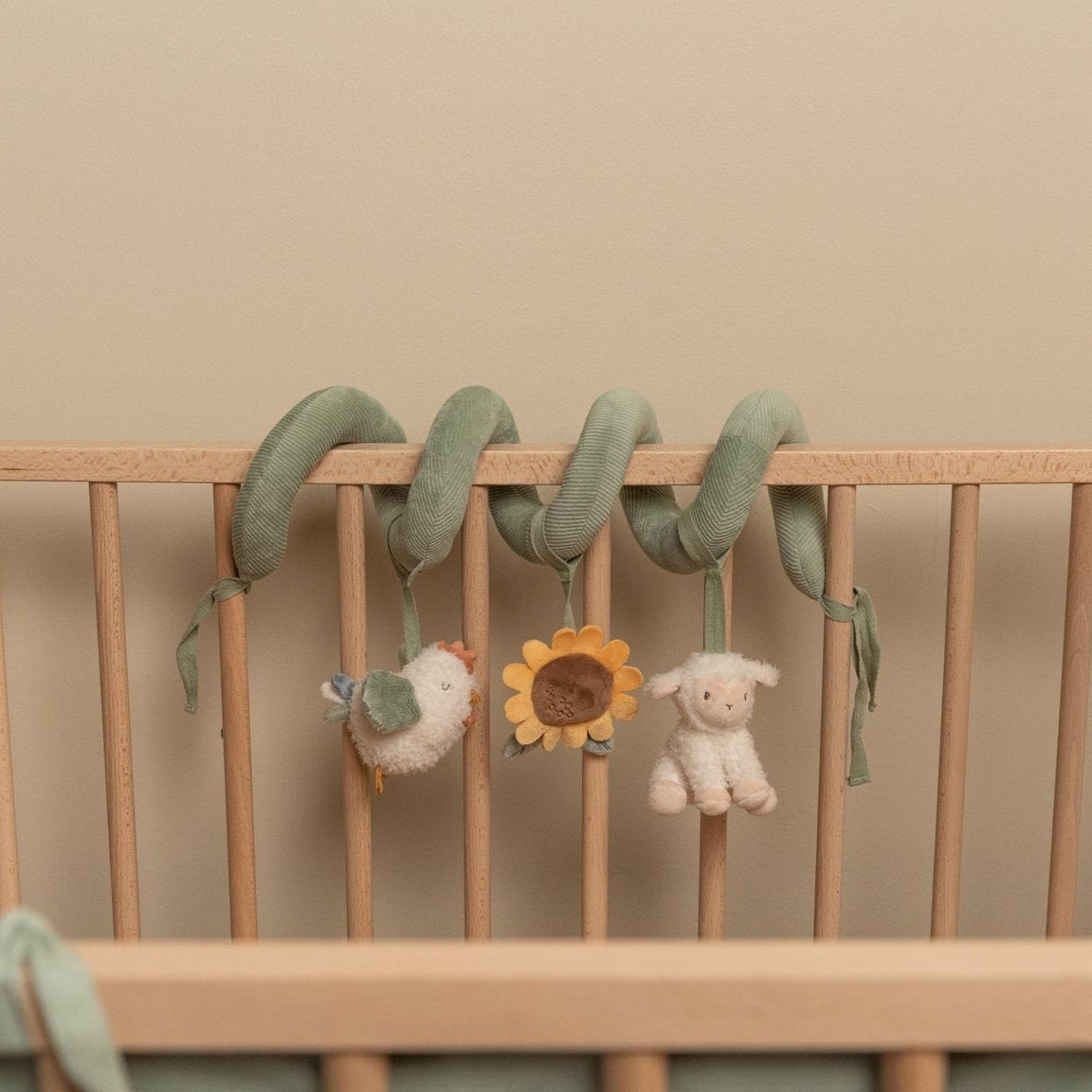 Wooden crib with hanging baby toys against a beige wall