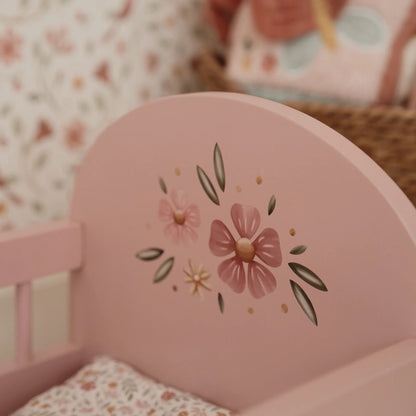 Pink Doll's bed with floral design in a softly blurred room.