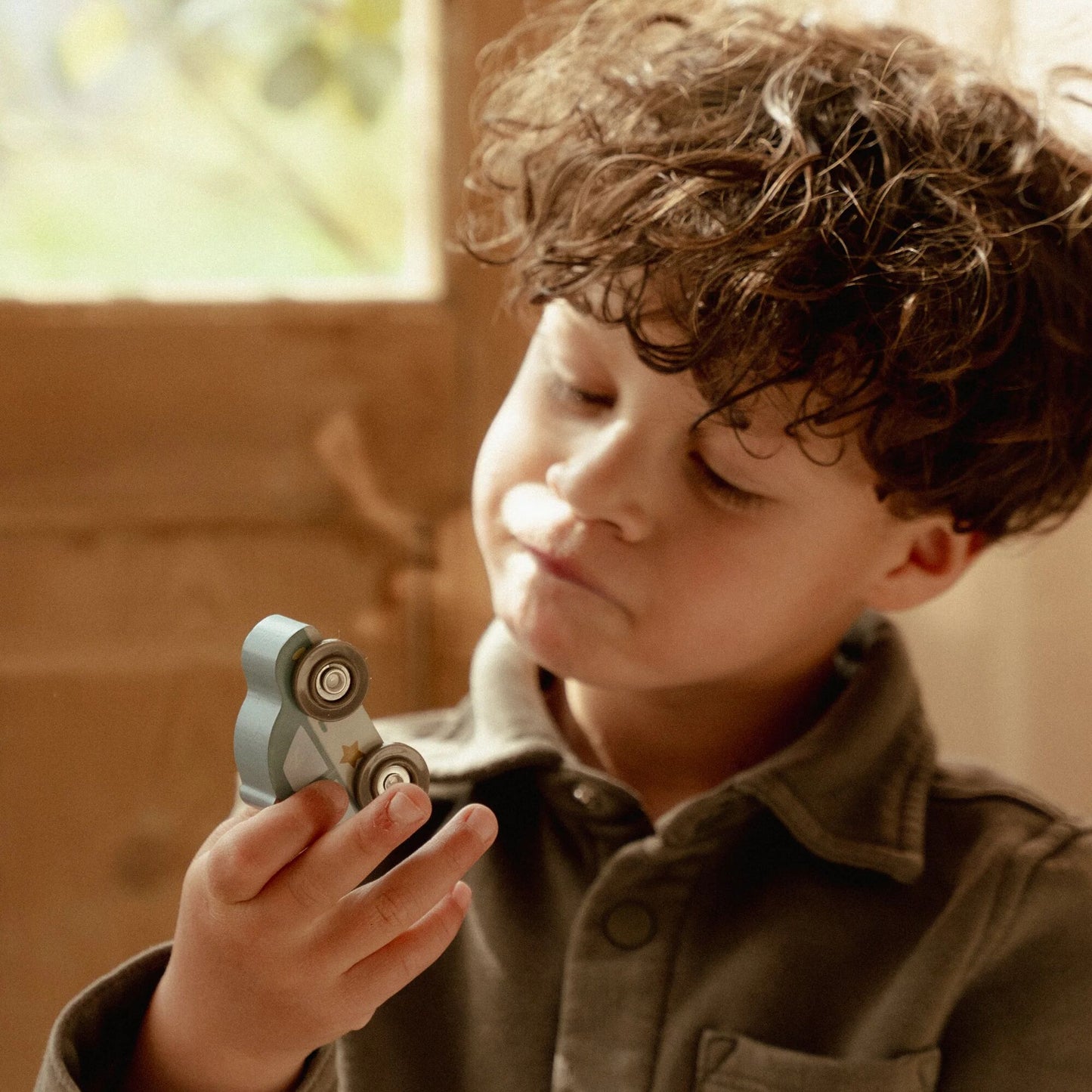 Child holding a small mechanical toy indoors