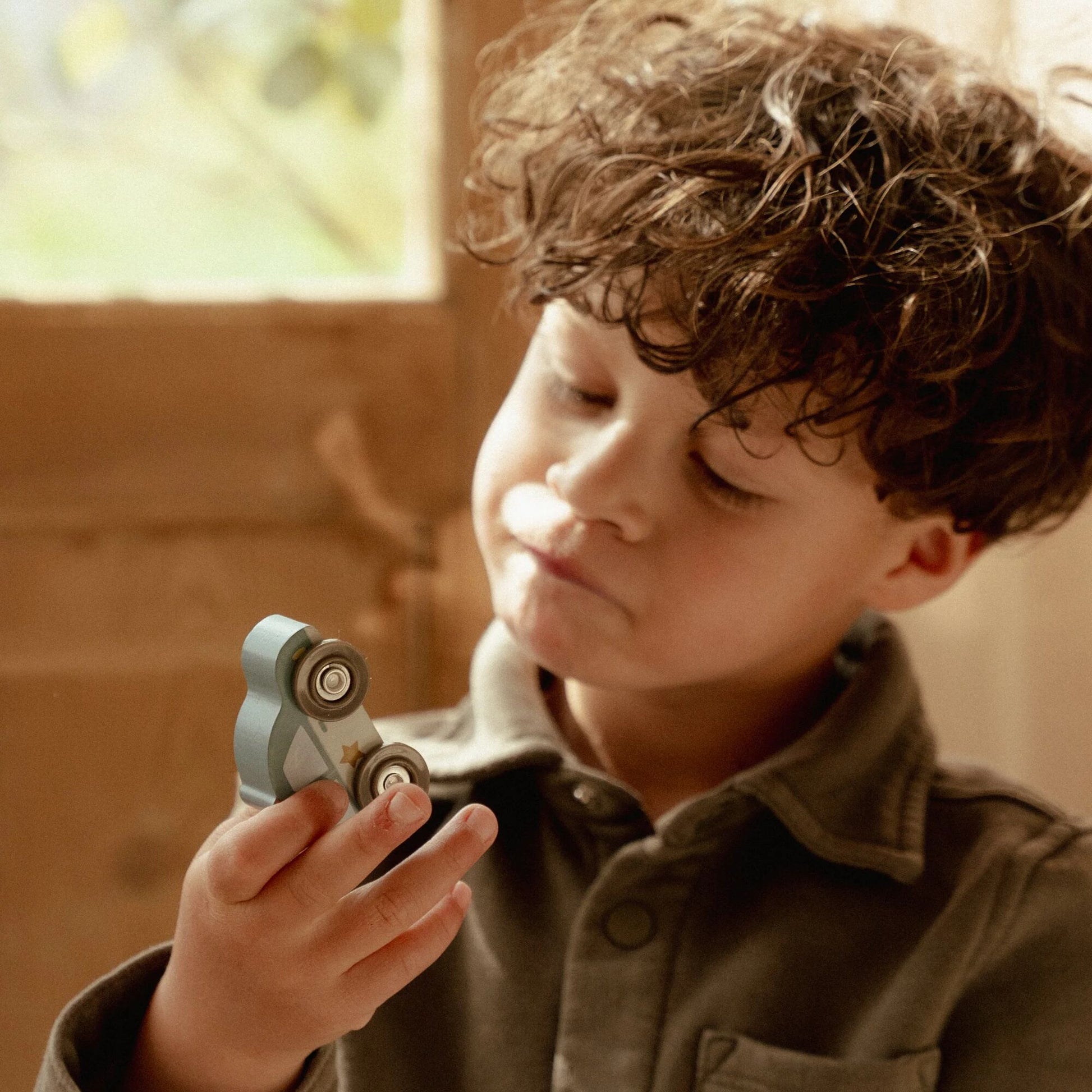 Child holding a small mechanical toy indoors