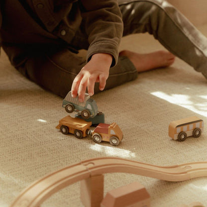 Child playing with wooden toy cars on a beige carpet