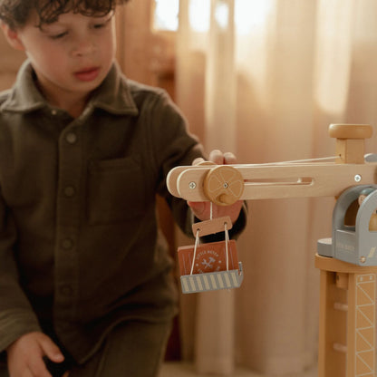 Child playing with a wooden toy crane in a warm indoor setting