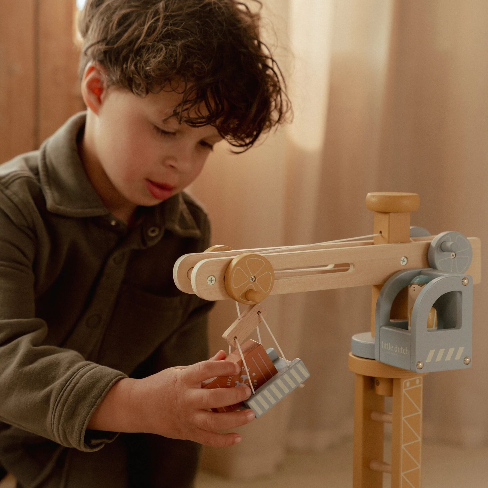 Child playing with a wooden toy crane
